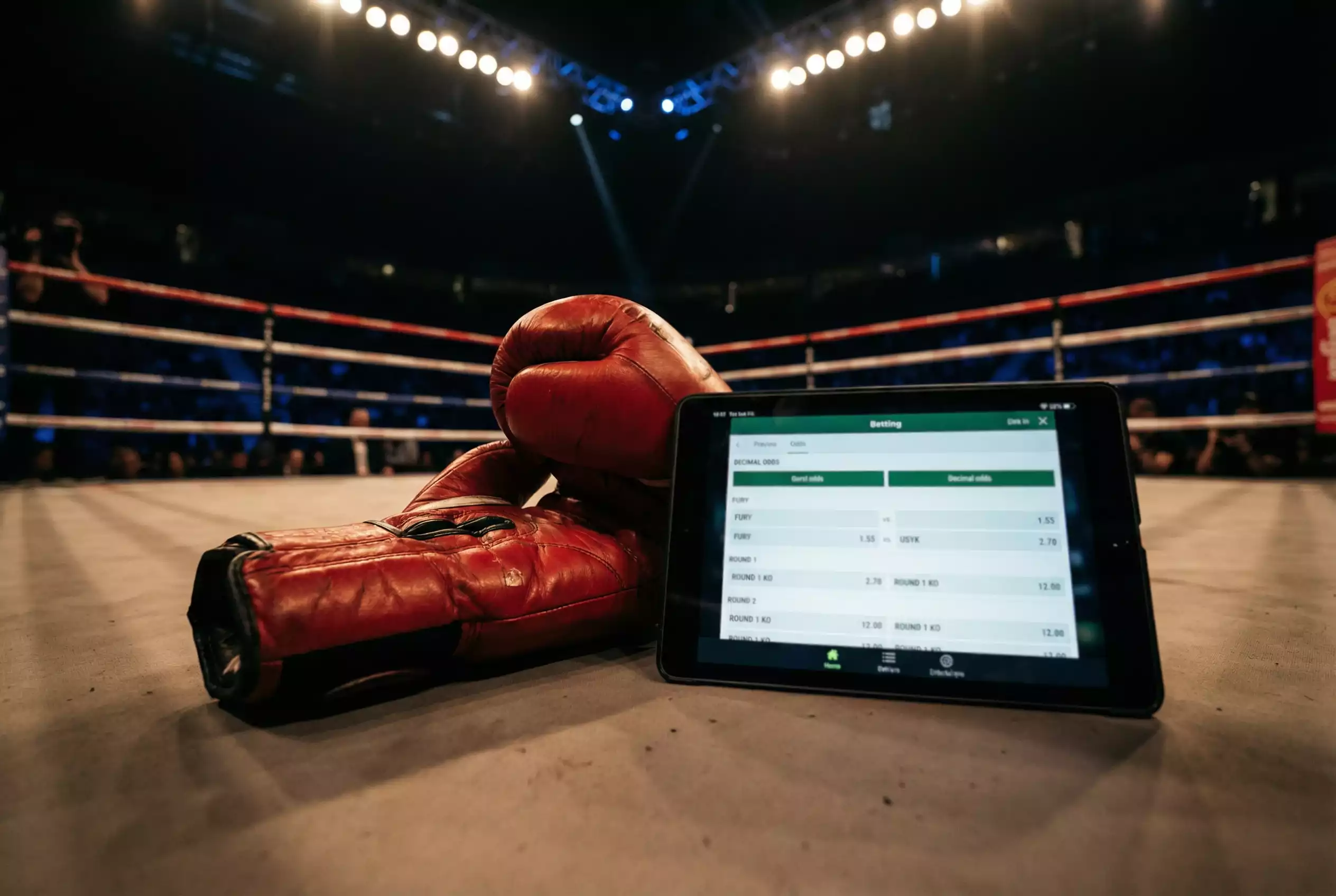 Guantes de boxeo junto a una pantalla con cuotas de moneyline para un combate profesional